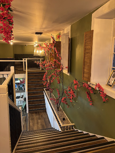  Interior view of the upstairs dining area and wooden staircase with floral decor 
at Greek Theory Falkirk